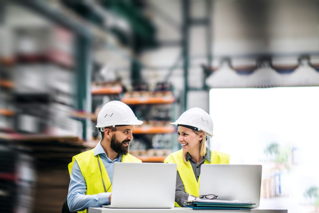 Two people conducting a safety audit or gap analysis on their laptops wearing high visibility vests